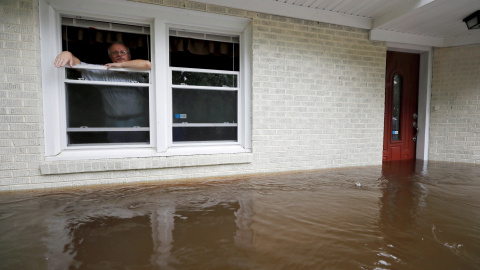 Un hombre espera ser rescatado después de que las precipitaciones hayan rodeado su casa | REUTERS/Jonathan Drake