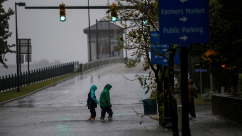 Dos personas en New Bern (Carolina del Norte) cruzan una calle inundada por el agua del río Neuse - REUTERS/Eduardo Munoz