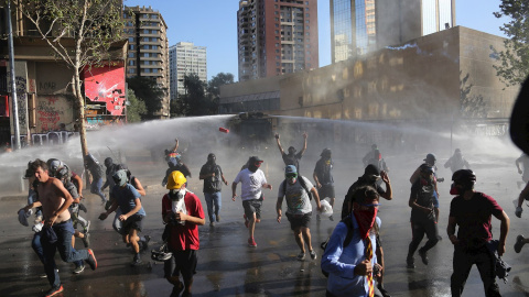 Un grupo de manifestantes huyen del camión lanza agua de la policía antidisturbios, durante una protesta contra el Gobierno del presidente Sebastián Piñera, en la plaza Italia de Santiago (Chile). - EFE/Elvis González Un grupo de manifestantes huyen del camión lanza agua de la policía antidisturbios, durante una protesta contra el Gobierno del presidente Sebastián Piñera, en la plaza Italia de Santiago (Chile). - EFE/Elvis González