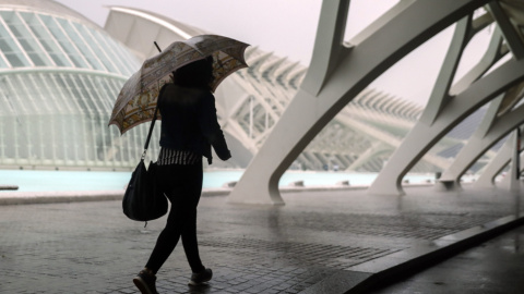 Una mujer se refugia de la lluvia con un paraguas en la Ciudad de las Ciencias de València./EFE Una mujer se refugia de la lluvia con un paraguas en la Ciudad de las Ciencias de València./EFE