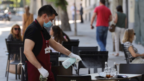 Un camarero desinfecta una mesa tras las marcha de los clientes la terraza de un bar del centro de Madrid, este miércoles. | EFE Un camarero desinfecta una mesa tras las marcha de los clientes la terraza de un bar del centro de Madrid, este miércoles. | EFE