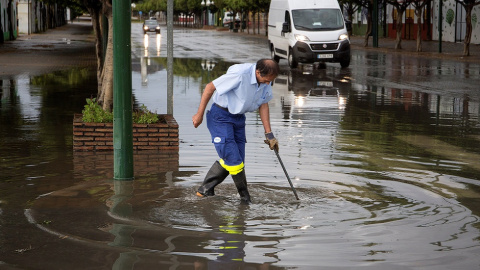 Un trabajador achicando el agua en mitad de la acera en Málaga./EFE