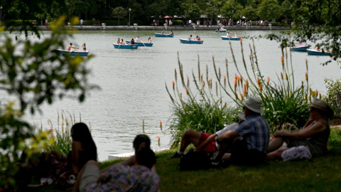 La gente se sienta a la sombra de los árboles mientras otros reman en botes en el Parque del Retiro en el centro de Madrid en la ola de calor de junio de 2022. La gente se sienta a la sombra de los árboles mientras otros reman en botes en el Parque del Retiro en el centro de Madrid en la ola de calor de junio de 2022.