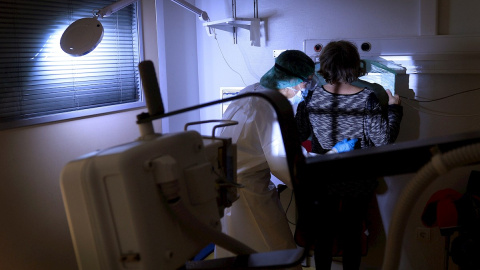 Una técnica de rayos X realiza una placa a una mujer con síntomas de covid.
