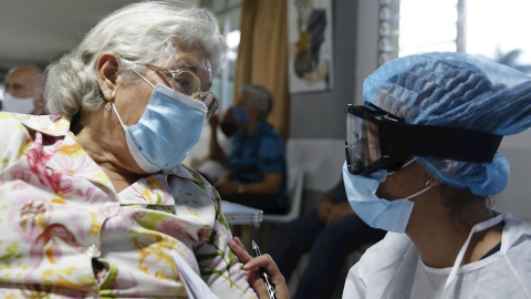 Una sanitaria conversa con una mujer antes de aplicarle la vacuna contra la covid en Medellín, Colombia.