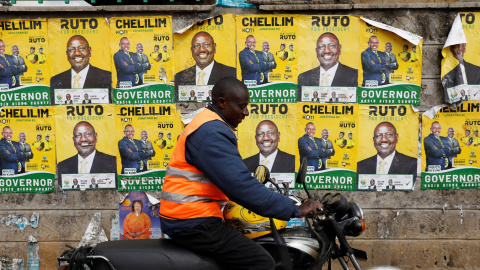 Un motorista pasa junta a una pared empapelada con los carteles electorales del actual vicepresidente de Kenia, y aspirante a la presencia, William Ruto, en las elecciones generales, en la localidad keniata de Eldoret. REUTERS/Baz Ratner Un motorista pasa junta a una pared empapelada con los carteles electorales del actual vicepresidente de Kenia, y aspirante a la presencia, William Ruto, en las elecciones generales, en la localidad keniata de Eldoret. REUTERS/Baz Ratner