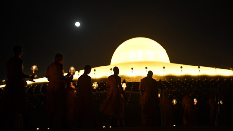 Monjes budistas llevan velas encendidas a las oraciones en el templo de Wat Phra Dhammakaya, cerca de Bangkok | AFP/ Lillian Suwanrumpha
