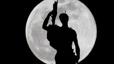 Estatua en la parte superior de la catedral del Duomo de Milán mientras se eleva la luna de nieve | AFP/ Andreas Solaro