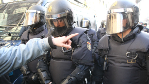 Una persona habla con unos agentes antidisturibios de la Policía Nacional en la inmediaciones de la calle Argumosa de Madrid. Eduardo Parra Europa Press