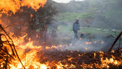 Un efectivo del Cuerpo de Bomberos del 112 de Cantabria durante las labores de extinción de un incendio forestal próximo a la localidad cántabra de Aes. El número de incendios activos en Cantabria ha bajado a 17 y los puntos más preocupantes están e
