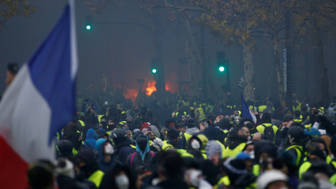 Entre el fuego y la bandera de Francia, cientos de manifestantes de los chalecos amarillos que protestan contra la subida de impuestos a los carburantes.- Stephane Mahe/REUTERS