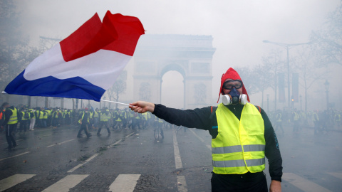 Un hombre sujeta una bandera de Francia. De fondo, el Arco del Triunfo. Stephane Mahe./REUTERS