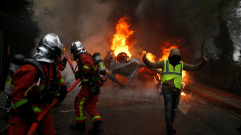 Los bomberos apagan el fuego durante las protestas de los chalecos amarillos en París.- Stephane Mahe/REUTERS