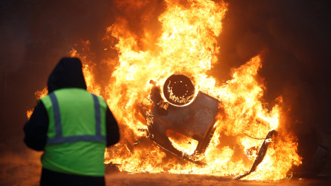 Un hombre ve como arde un coche. Stephane Mahe/REUTERS