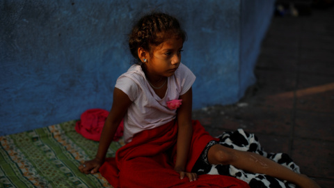 Una niña nicaragüense se despierta después de dormir en el suelo mientras espera en la fila para ingresar a la COMAR. / Reuters