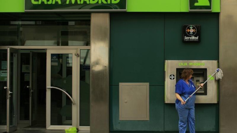 Una empleada limpia la facahda de una oficina de Caja Madrid en Sevilla. REUTERS/Marcelo del Pozo Una empleada limpia la facahda de una oficina de Caja Madrid en Sevilla. REUTERS/Marcelo del Pozo