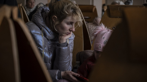 Anna entretiene con el teléfono móvil a su hija de 2 años, mientras espera a que llegue su tren en Odesa. Viene huyendo desde la ciudad de Mikolaev, bombardeada por los rusos desde hace varios días.