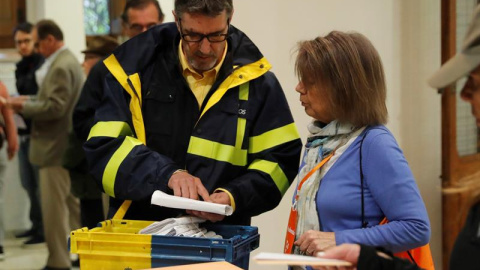 Un funcionario de correos hace entrega a la presidenta de una mesa del colegio electoral del Colegio Nuestra Señora del Pilar votos emitidos por correo. / EFE