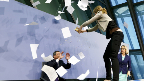 Una activista salta sobre la mesa desde la que el presidente del BCE, Mario Draghi, ofrece su rueda de prensa mensual en la sede de la entidad monetaria de la Eurozona. REUTERS/Ralph Orlowski