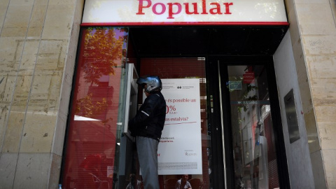 Un hombre saca dinero de un cajero automático del Banco Popular, en la localidad barcelonesa de Vilanova i la Geltru, en una foto del 7 de junio de 2017, el día que se anunció la resolución de la entidad. AFP/Lluis Gené Un hombre saca dinero de un cajero automático del Banco Popular, en la localidad barcelonesa de Vilanova i la Geltru, en una foto del 7 de junio de 2017, el día que se anunció la resolución de la entidad. AFP/Lluis Gené