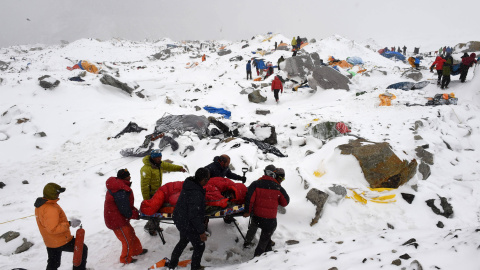Los equipos de rescate usan una camilla improvisada para llevar a una persona herida después de la avalancha provocada el sábado por el terremoto, arrasando el campo base del Everest.- AFP PHOTO / Roberto SCHMIDT