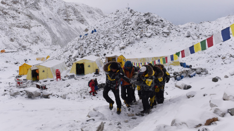 Una persona herida es llevada por los miembros de rescate para ser transportada en helicóptero desde el campamento base del Everest este domingo.Los cuerpos de los fallecidos se encuentran en tiendas de campaña de color naranja. -AFP PHOTO 