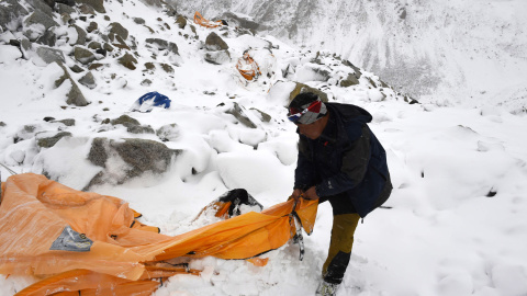 En esta fotografía tomada el sábado, el guía de la expedición Pasang Sherpa busca supervivientes entre tiendas de campaña arrolladas por la avalancha producida en el Everest por el primer terremoto.- AFP PHOTO / Roberto SCHMIDT