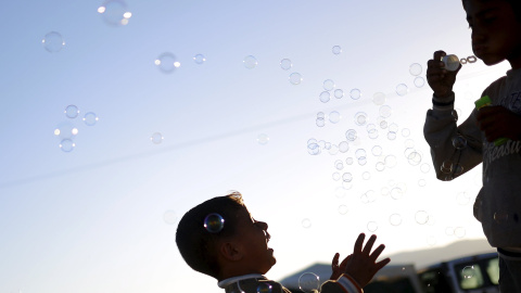 Niños juegan con burbujas de jabón en un campamento improvisado para refugiados en la frontera entre Grecia y Macedonia, cerca de la localidad de Idomeni. REUTERS/Stoyan Nenov