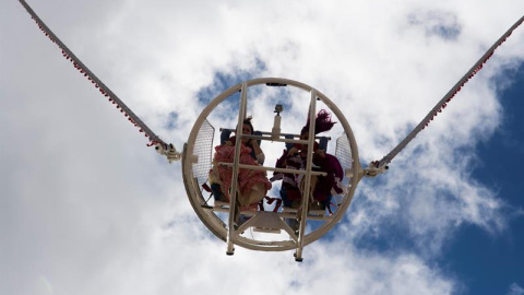 Dos mujeres vestidas de flamenca dentro de una atracción en la Feria de Abril de Sevilla. EFE/Raúl Caro