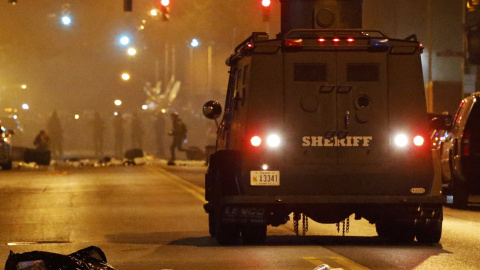A police armoured car moves down a street as clouds of smoke and crowd control agents rise shortly after the deadline for a city-wide curfew passed in Baltimore. REUTERS/Jim Bourg