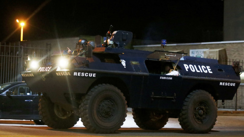 A police armoured car moves down a street as clouds of smoke and crowd control agents rise shortly after the deadline for a city-wide curfew passed in Baltimore, Maryland. REUTERS/Jim Bourg