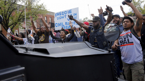 Demonstrators march in front of a Baltimore police vehicle down Pennsylvania Avenue, a day after it was looted and set ablaze in protest for the death of 25-year-old black man Freddie Gray who died in police custody in Baltimore. REUTERS/Sh