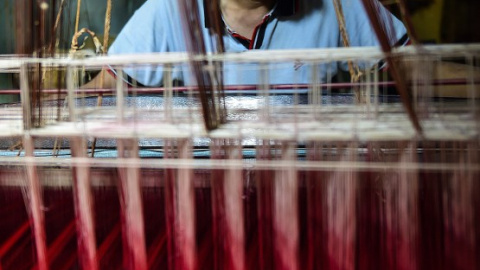 Un tejedor trabaja en una fábrica de tela en Dacca. - AFP