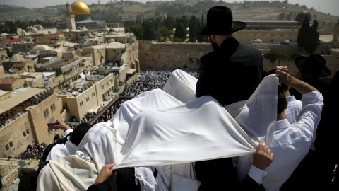 Unos fieles judíos se cubren cpn unas mantas para orar en la azotea con vistas al Muro Occidental durante una bendición sacerdotal especial para la Pascua en la Ciudad Vieja de Jerusalén. REUTERS/Ronen Zvulun