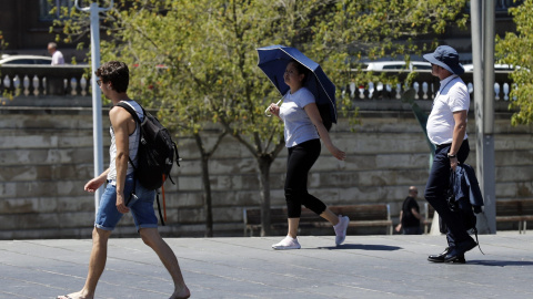 Una mujer se protege con un paraguas del calor en Bilbao, donde los valores registrados este viernes se sitúan entre 10 y 15 grados por encima de lo normal en el noroeste peninsular. | EFE