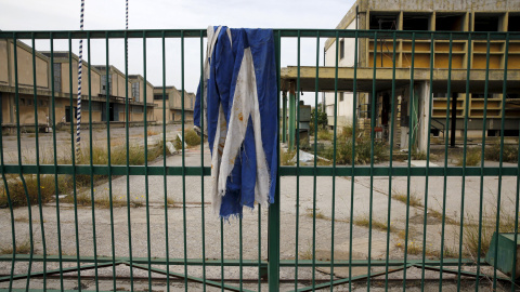 Una bandera griega sobre la puerta de una fábrica de aceite de cocina desierta que se cerró en 1996 en la ciudad de Elefsina, en la región Sterea Hellas, Grecia.- REUTERS / Yannis Behrakis