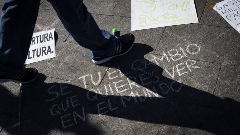 Una persona pasa ante una pintada en el suelo en la madrileña Puerta del Sol donde se celebra hoy el cuarto aniversario del movimiento 15M. EFE/Luca Piergiovanni