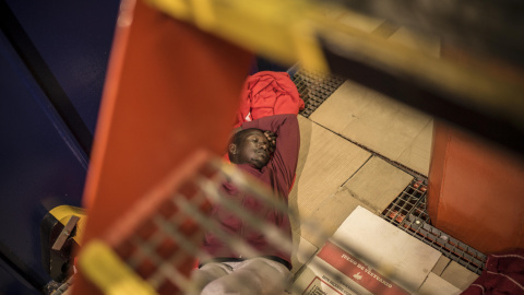 Un joven senagalés trata de dormir bajo la escalera del barco María Zambrano, en el puerto de Algeciras. Durante al menos tres noches, más de 200 migrantes rescatados han tenido que dormir hacinados a bordo por la falta de espacio en otras 