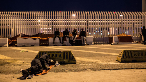 Un migrante duerme en el suelo del puerto del Algeciras, junto a más de 170 personas rescatadas por Salvamento Marítimo durante el fin de semana. JAIRO VARGAS