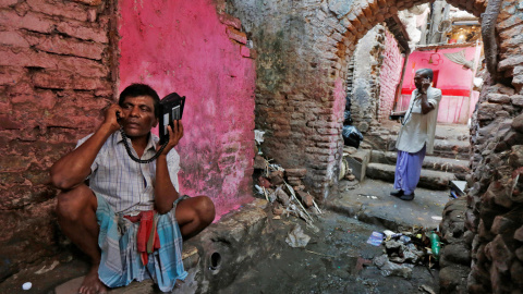 Trabajadores hablan con teléfonos inalámbricos en un callejón en Calcuta. REUTERS/Rupak De Chowdhuri