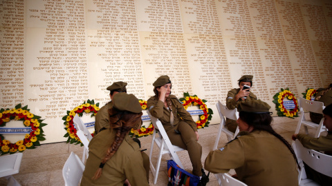 Soldadas israelíes sentados frente a un monumento grabado con los nombres de soldados israelíes, mientras esperan el inicio  de la ceremonia del Día Memorial en Jerusalén, Israel. REUTERS/Ronen Zvulun