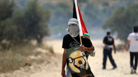 Un manifestante enmascarado sostiene una bandera palestina durante los enfrentamientos con soldados israelíes en una protesta delante del día de la Nakba , en la localidad cisjordana de Bilin cerca de Ramallah, 13 de mayo de 2016. REUTERS / Un manifestante enmascarado sostiene una bandera palestina durante los enfrentamientos con soldados israelíes en una protesta delante del día de la Nakba , en la localidad cisjordana de Bilin cerca de Ramallah, 13 de mayo de 2016. REUTERS /