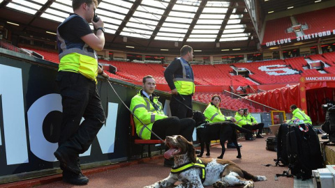 Varios agentes de seguridad y un perro en el interior del estadio Old Trafford tras evacuarlo. /EFE Varios agentes de seguridad y un perro en el interior del estadio Old Trafford tras evacuarlo. /EFE
