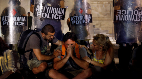 Yiorgos Avramidis, de 43 años, casado y con dos hijos de tres y seis años, es consolado por sus colegas frente a una línea policial en 2013. /  REUTERS - YANNIS BEHRAKIS