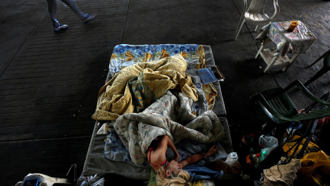 Marialena, una persona sin hogar de 42 años que padece SIDA y exdrogadicta, duerme bajo un puente en el centro de Atenas. / REUTERS - YANNIS BEHRAKIS