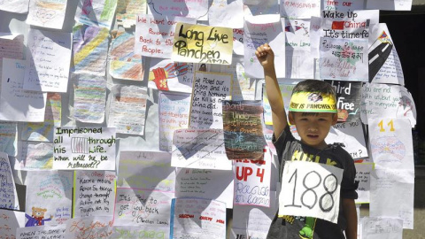 Un niño posa delante de una pared cubierta con mensajes de activistas tibetanos con motivo de la conmemoración del 21 aniversario del secuestro de un niño tibetano de siete años considerado como la reencarnación del Panchen Lama, en Dharams
