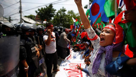 Una simpatizante de las minorías étnicas grita consignas antigobierno frente a los agentes antidisturbios durante una marcha hacia la sede del Gobierno para protestar a favor de una nueva división administrativa en Nepal, en Katmandú, Nepal