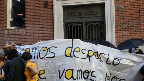 Varios activistas tapan la puerta mientras otros entran en el edificio que han okupado en el centro de Madrid.- ALEJANDRO TORRÚS