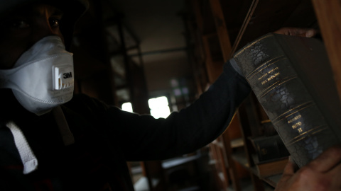 Un activista observa libros antiguos almacenados en el edificio okupado en Madrid.- JAIRO VARGAS