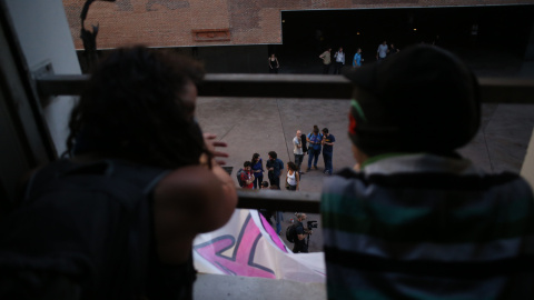 Dos activistas miran por la ventana del edificio que han okupado en el centro de Madrid.- JAIRO VARGAS